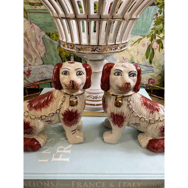 A charming pair of vintage Staffordshire-style spaniel dog figurines, beautifully rendered in a warm cream glaze with rich...