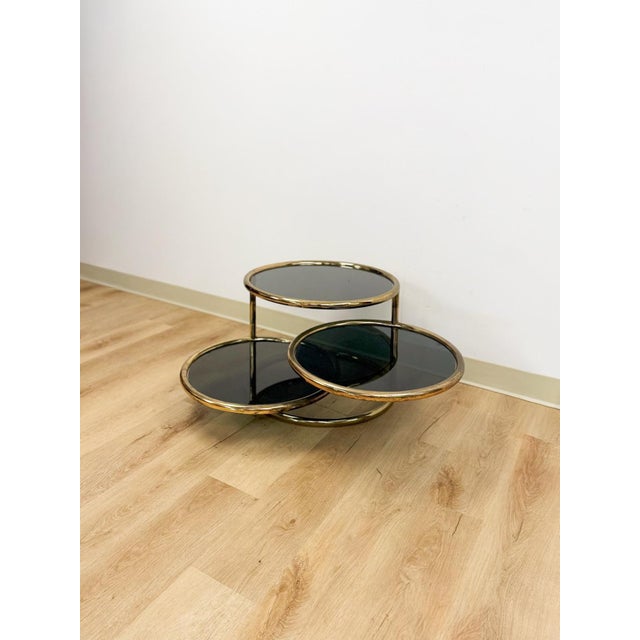 This extraordinary vintage Milo Baughman style tubular chrome 3-tier coffee table with swivel action and smokey glass is a...