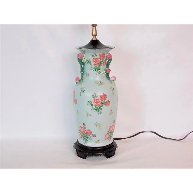 Asian rose porcelain urn table lamp with a floral design. Mounted on a dark wood base. Wired and in working condition with...
