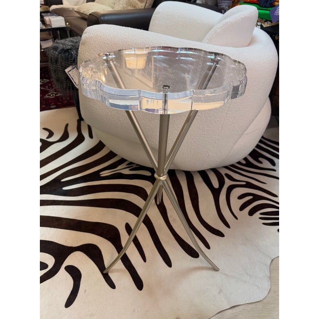 Round side table in lucite with a cinched crisscross silver finish metal base. The feet terminate with a delicate splay...
