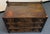 A striking three-drawer chest with a rich dark wood finish and rustic, architectural character. Each drawer features a...