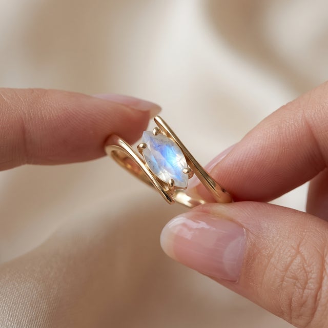 Experience captivating radiance with this delicate bypass ring set with a glowing marquise-cut Rainbow Moonstone. Designed...