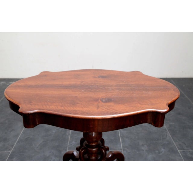 Carlo X table in solid cherry wood, with four finely carved curved legs connected to a central twisted trunk, supporting a...