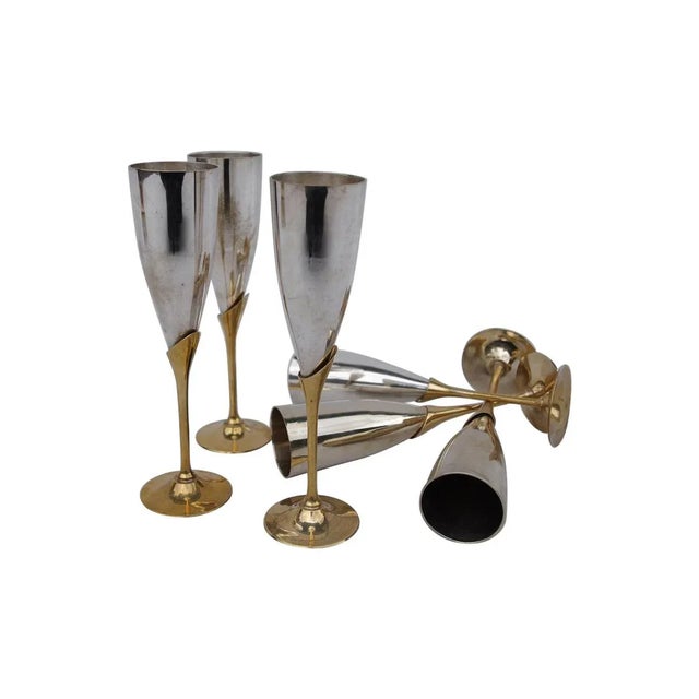 Six silvery and gilt brass champagne flutes. The silvered brass upper part stands on a gilt brass part in the shape of the...
