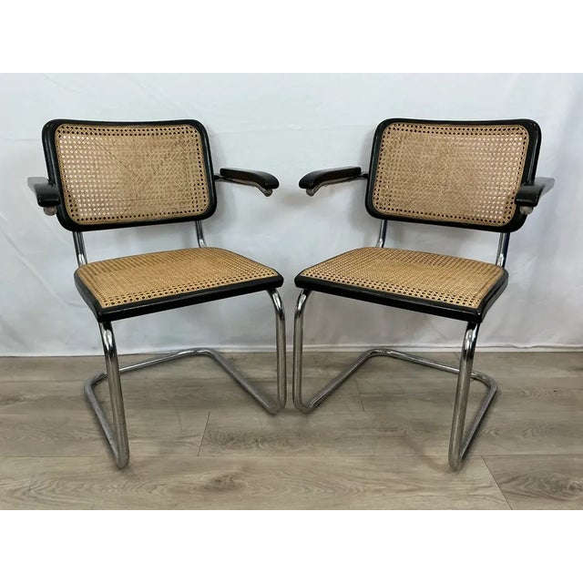 Two Cesca chairs also known as S64 with tubular steel cantilevered frame with polished chrome finish, black lacquered...