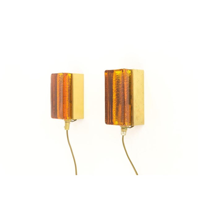 A set of two amber glass and brass Atlantic wall lamps that are produced by Danish lighting manufacturer Vitrika in the...
