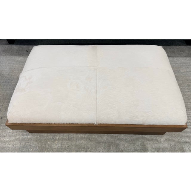 oversized ottoman featuring luxurious white pony hair-on-hide upholstery paired with a substantial white oak base in a...