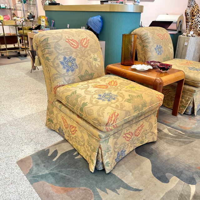 A beautiful vintage armless upholstered slipper chair with patterned fabric and a skirted base with tassel detail on...
