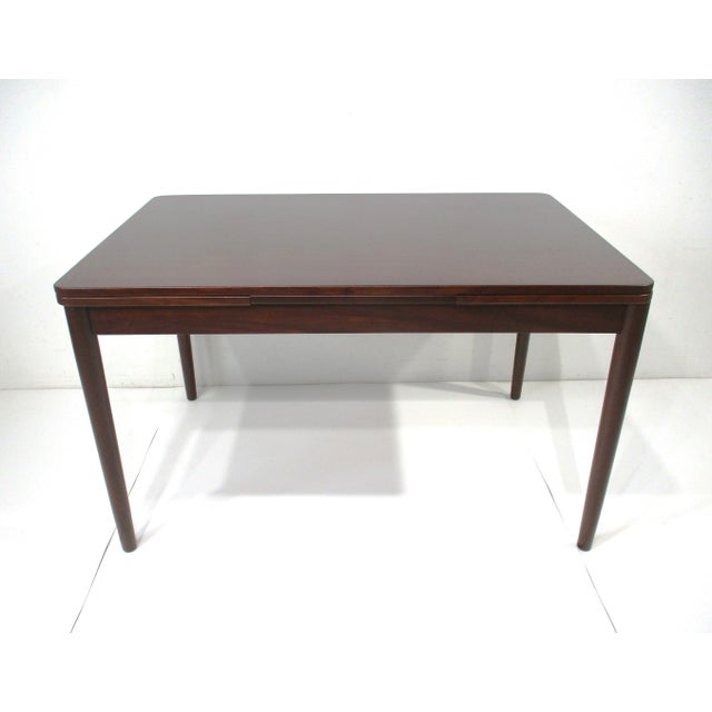 A dark teak wood dining table with extendable pull out leaves to each end and narrow depth perfect for a smaller dining...