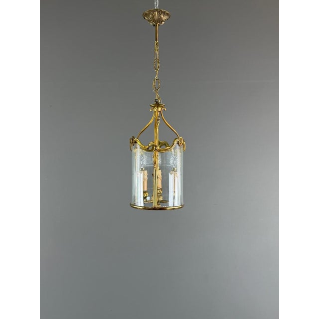 An elegant Louis XV style cylindrical lantern in gilt bronze, decorated with scrolls, volutes, and foliate motifs. The...