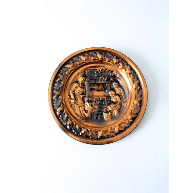 This is a vintage raised relief copper plate. The decorative wall hanging features a central image of a family filling...