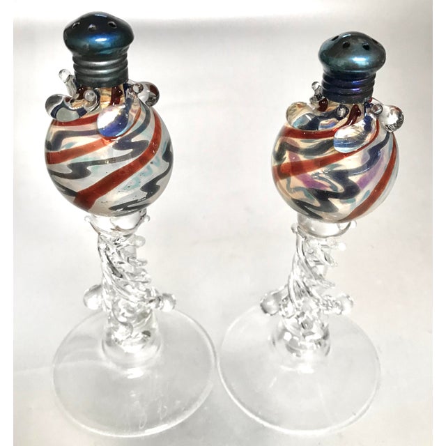 A pair of Venetian style hand blown salt and pepper shakers with spiral patterns of blue and red blended with opalescent...