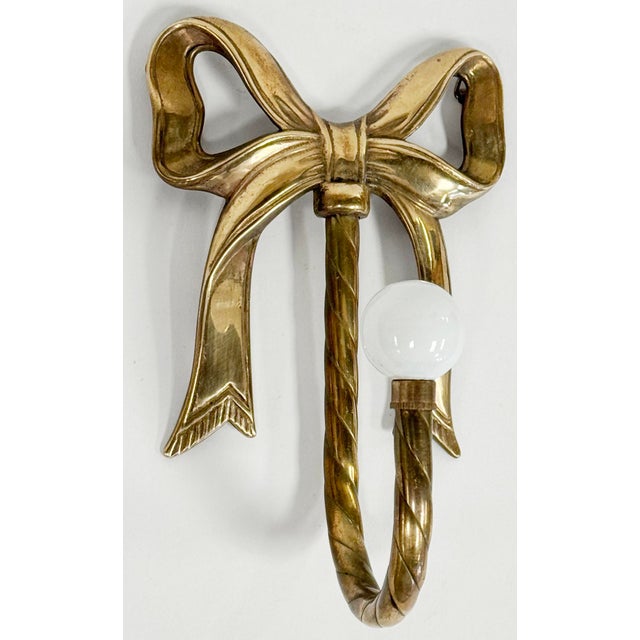 Vintage detailed brass ribbon bow wall hook with ceramic knob. Patina to brass.