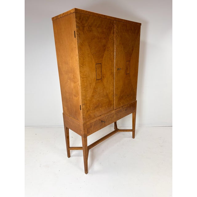 Swedish Cabinet. Birch veneer with decorative inlay. 2 large doors conceal interior adjustable shelves. 2 small drawers...