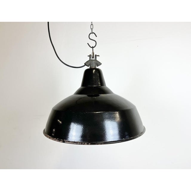 Industrial black enamel pendant light made in former Czechoslovakia during the 1950s. White enamel inside the shade. Cast...