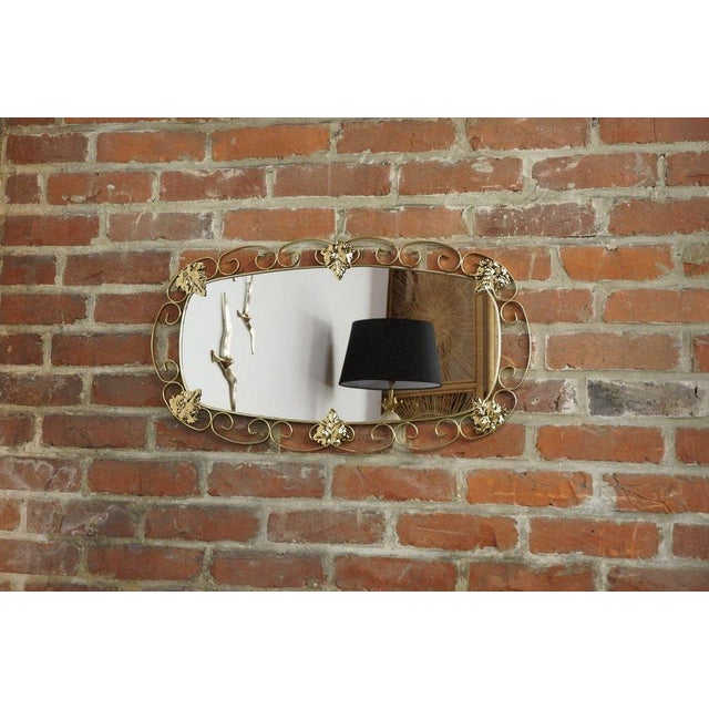 Oval mirror from the 1950s-60s; brass structure with scrolls and foliage, all in excellent condition.