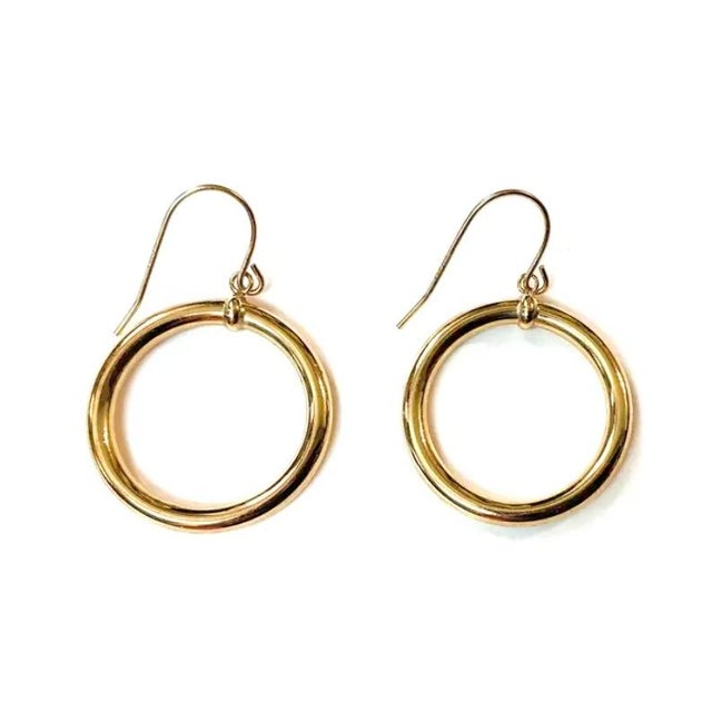 Vintage 14K Gold Dangle Hoop Earrings. Each earring features a classic circular hoop suspended from a delicate wire hook,...