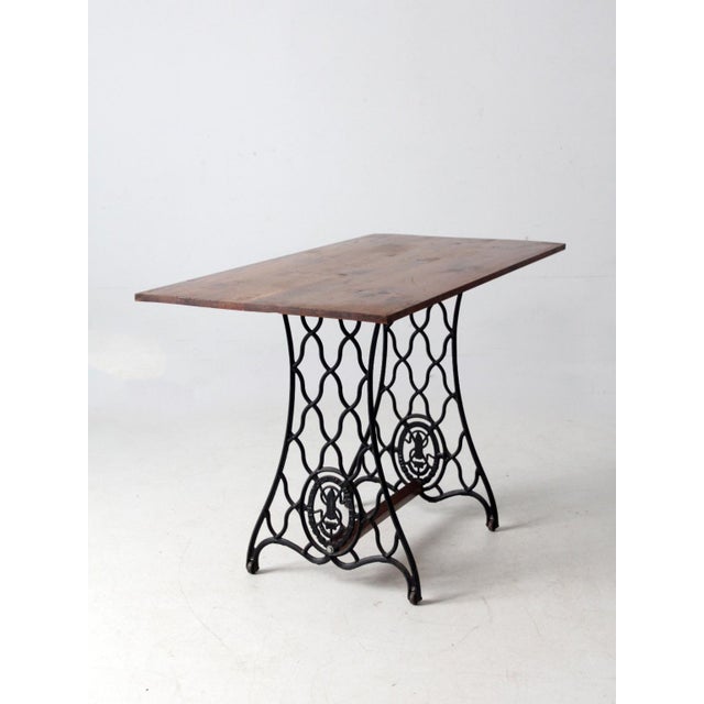 Vintage table featuring an antique Singer cast iron base paired with a solid wood top. The sculptural iron base brings...