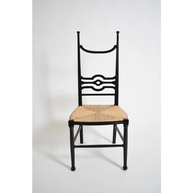 Arts & Crafts ebonised wood fireside chair, 1900s. Ebonised wood fireside chair with a high back receiving an openwork...