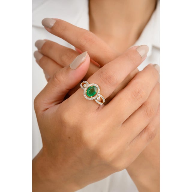 This modern designer ring showcases a stunning natural oval-cut emerald, flanked by brilliant diamonds that enhance its...