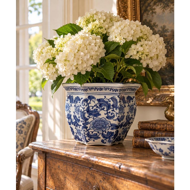 A classic blue and white porcelain planter, rendered in a softly faceted, scalloped form that feels both tailored and...