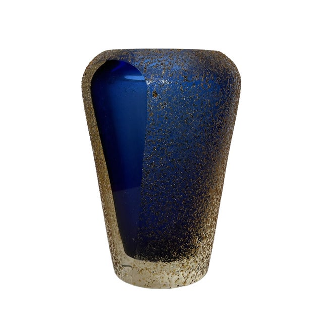 The Mid Century Modern heavy glass vase is almost round except for a wide flat front showing the blue vase encased in...