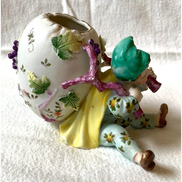Whimsical and charming small bisque floral vase in the form of a young boy carrying a large egg vessel on his back. We...