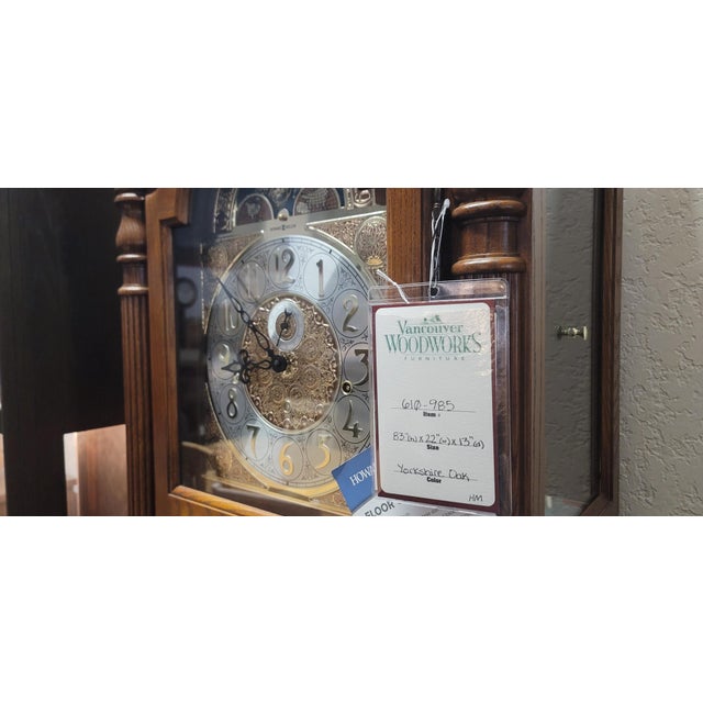 This 77th Anniversary Edition floor clock features an arched bonnet pediment highlighted by a decorative shell and vine...