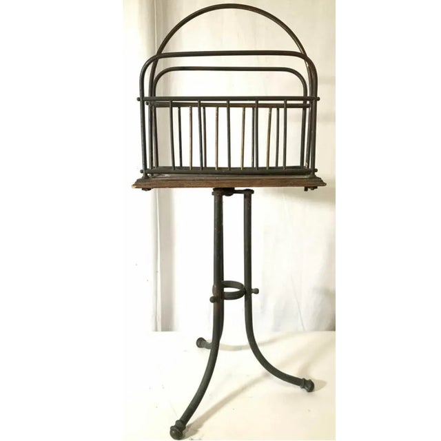 A lovely arts and crafts antique magazine rack. Piece is metal with wood and features tripod style legs. Measures...