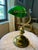 Classic vintage banker’s-style table lamp featuring a distinctive glossy green glass shade, polished brass-tone adjustable...