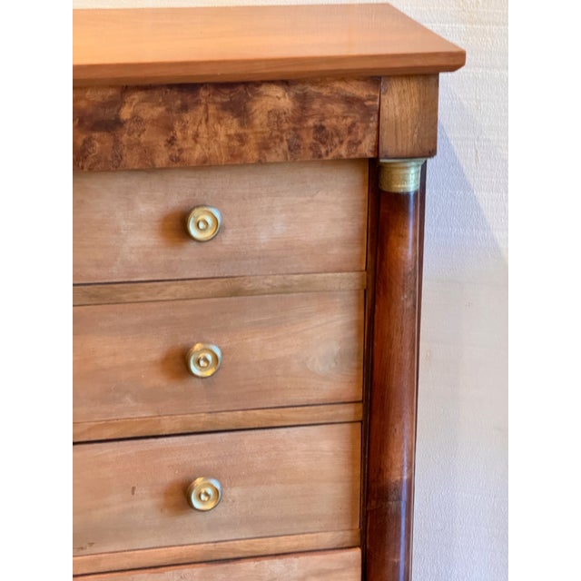 A neat little Empire chest with five drawers, flanking columns with brass capitals and bases, and a burr walnut frieze...