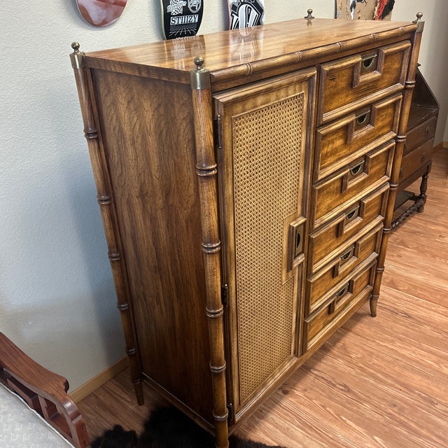 A faux bamboo nightstand by Stanley Furniture, circa 1970s. Two cabinet doors fronted in woven cane with Greek key...