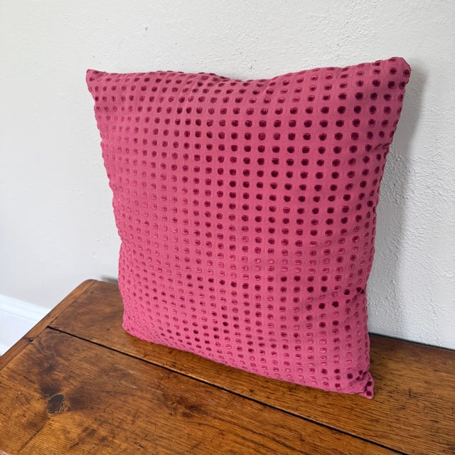Square knife edge pillow in a raspberry pink woven ground with rows of raised cut velvet dots in a deeper berry shade....