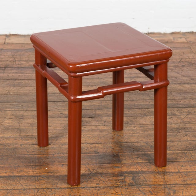 A Chinese late Qing Dynasty period side table or stool from the early 20th century, with red lacquer, humpback stretchers...
