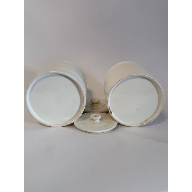 A beautifully preserved pair of late 19th-century English ironstone pantry jars, each retaining its original matching lid...