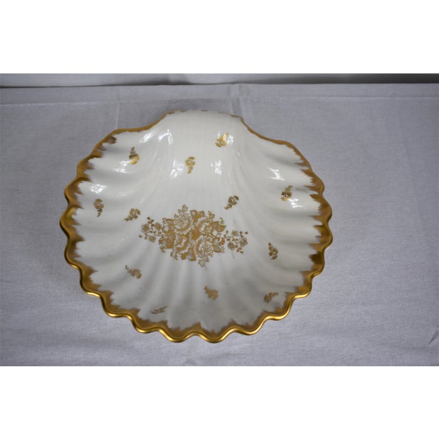 Vintage French bowl in the shape of a shell decorated with gold flowers and gold along the scalloped edge of the bowl....