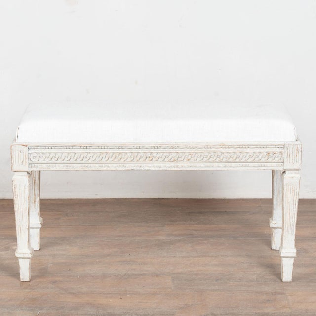Early 19th century Swedish Gustavian small bench, crafted in pine. The bench features a decorative carved skirt and fluted...