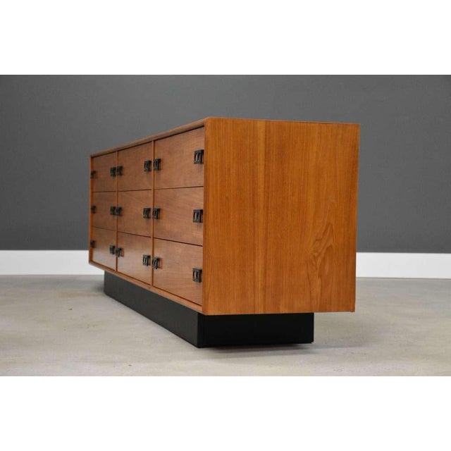A mid century modern teak nine drawer dresser with a black plinth base and black finger pulls. Made in Canada. Circa...