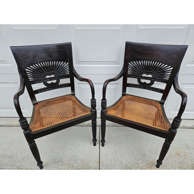 A stylish pair of Anglo-Indian or British Colonial style armchairs with a sunburst pattern backrest, uniquely carved arms,...