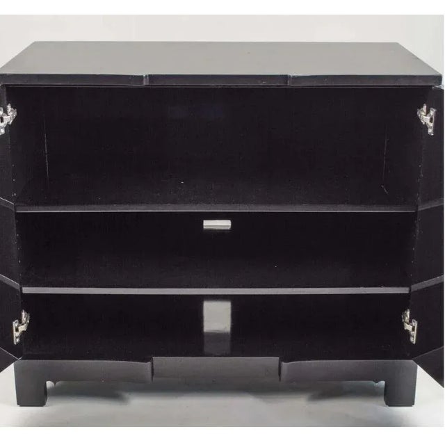 Modern black lacquered cabinet with curved front appearing as three doors. Cabinet has two doors that swing open to reveal...