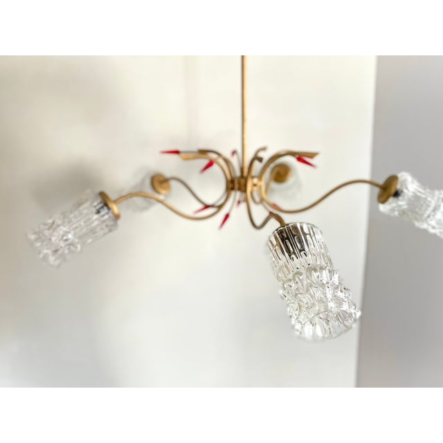 French Mid-Century Modern chandelier from the 1960s featuring five curved brass-tone arms, original textured glass shades,...