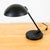 Black desk lamp. Featuring a circular shade and round metal base. Standard socket. Works as intended. Unsigned American...