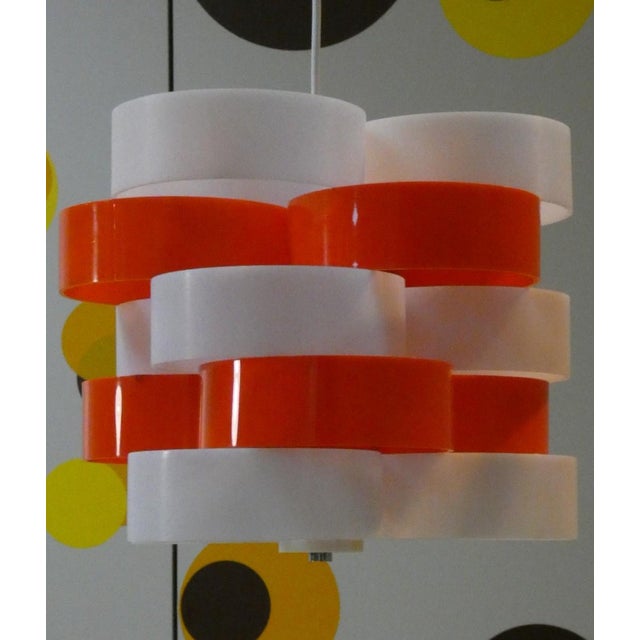 Chandelier with white and orange circular plastic elements\. The height is adjustable and the design is by stilux milano,...