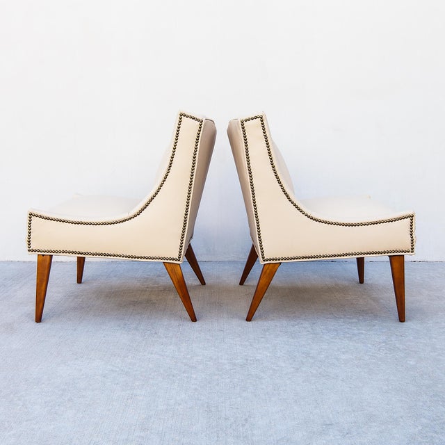 A pair of low profile leather lounge chairs with antiqued nailhead detailing by Selig, made in the United States c. late...