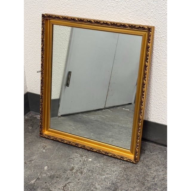 Design Plus Gallery presents a Vintage Ornate Gold Framed Mirror. The mirror has a gold tone frame with raised floral and...