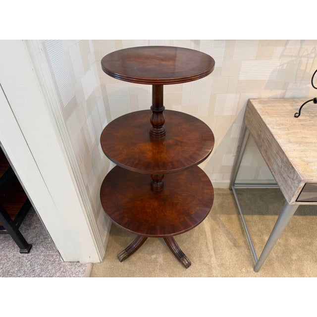 Elegant three-tier mahogany dumbwaiter table with graduated round shelves and a turned central column. The rich, warm...