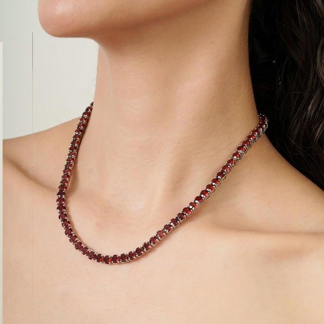 A refined garnet tennis necklace crafted in 925 sterling silver, featuring 81 round-cut gemstones (5 mm each) with a total...