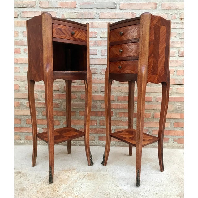 Pair of French walnut bedside tables adorned with fine Louis XV marquetry from the early 19th century. This pair of French...