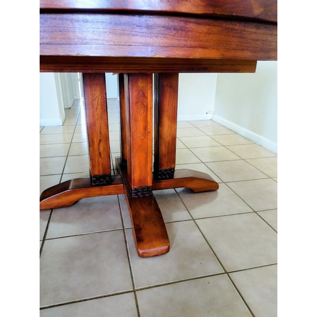 Dining table made of solid pine, decorated with ceramic accents and black leather strips on the legs. The table features a...