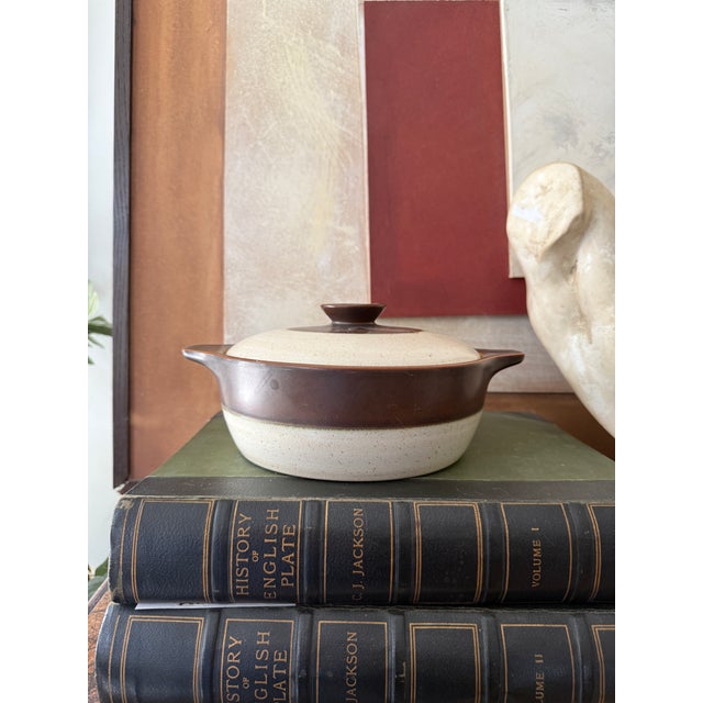 A classic Denby Langley England stoneware casserole in a warm, earthy two-tone glaze—deep chocolate brown over a soft...